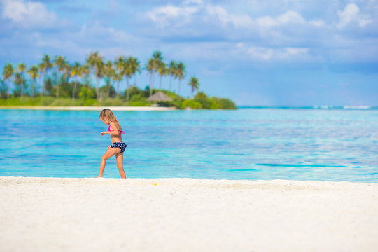 Adorable happy little girl have fun at shallow water on beach