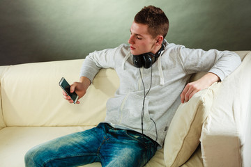 man on couch with headphones smartphone