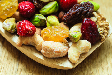 Varieties of dried fruits and nuts on wooden spoon.