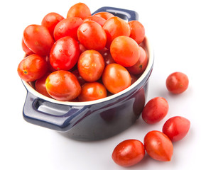 Bite sized red cherry grape tomato in blue pot over white background