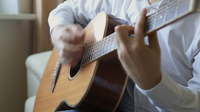 guitarist plays on acoustic guitar at home