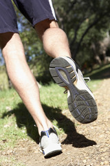 Fototapeta premium Close Up Of Man's Feet Jogging Along Woodland Path