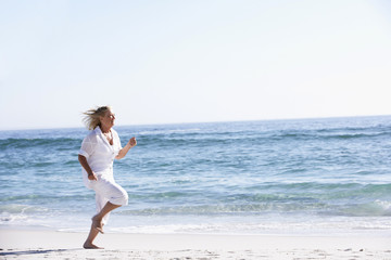 Fototapeta na wymiar Senior Woman Running along Sandy Beach