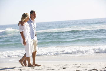 Senior Couple On Holiday Walking Along Sandy Beach