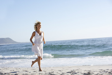 Fototapeta na wymiar Casually Dressed Young Woman Running Along Beach