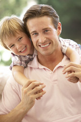 Obraz premium Father With Son Laughing Together On Sofa