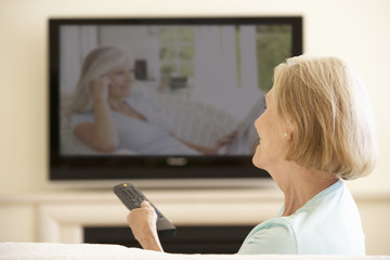 Senior Woman Watching Widescreen TV At Home