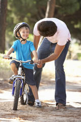 Fototapeta na wymiar Father Teaching Son To Ride Bicycle
