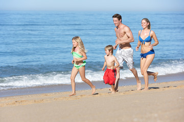 Family Enjoying Beach Holiday Running Along Beach