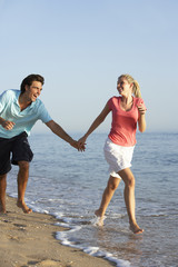 Young Couple Running Along Beach
