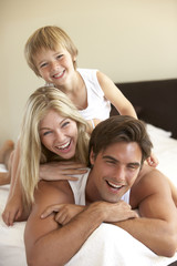 Young Family Relaxing On Bed