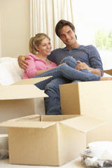 Fototapeta na wymiar Young Couple Moving Into New Home Surrounded By Packing Boxes