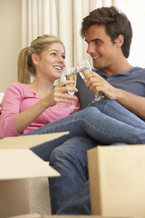 Young Couple Moving Into New Home Celebrating With Champagne