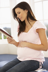 Pregnant Woman Reading Information Booklet At Home