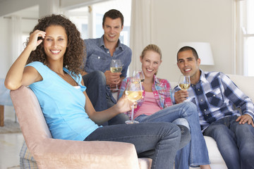 Group Of Friends Relaxing On Sofa Drinking Wine At Home Together
