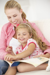 Fototapeta na wymiar Mother And Daughter Reading Book In Bedroom