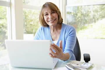 Senior Hispanic Woman Using Laptop In Home Office