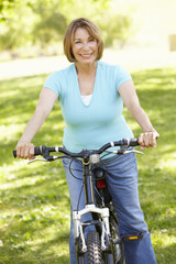 Naklejka premium Senior Hispanic Woman Cycling In Park