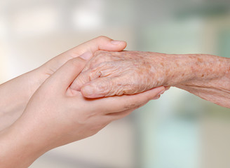 Fototapeta premium Young nurse holding old patient hand in hospital