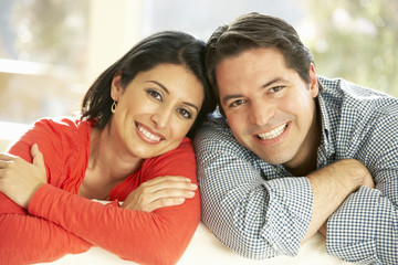 Hispanic Couple Relaxing At Home On Sofa