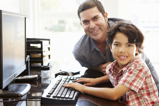 Hispanic father and son using computer at home