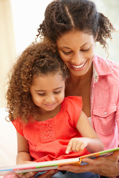 Mixed race woman and daughter reading