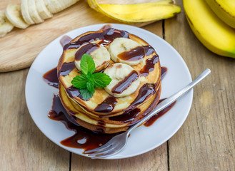 Stack of pancakes with banana and chocolate syrup