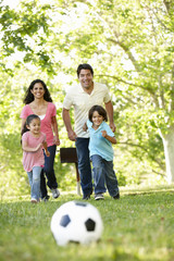 Young Hispanic Family Playing Football In Park