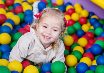 happy little girl playing on colorful balls