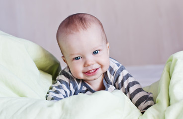 Happy baby in bed on his