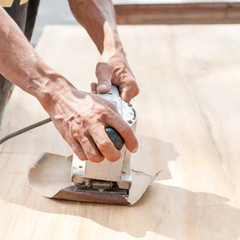 Hand of worker sanding the old wood table.