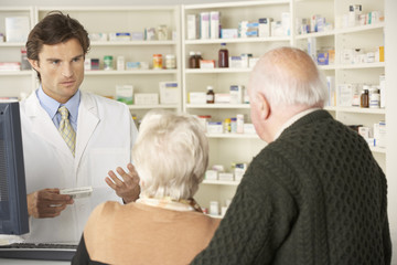 Pharmacist in pharmacy with senior couple