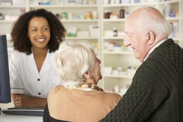 Senior couple in pharmacy with pharmacist