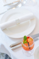 Holiday table setting/Cocktail with strawberry slices and a sprig of mint on served table