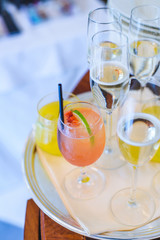 Tray with alcoholic beverages on a wooden table/Glasses of champagne and other cold cocktails on a silver tray.