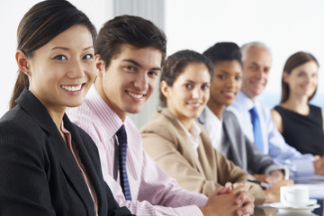 Fototapeta premium Line Of Business People Listening To Presentation Seated At Glass Boardroom Table