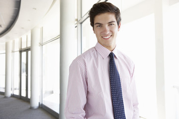 Fototapeta premium Portrait Of Young Businessman Standing In Corridor Of Modern Office Building