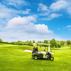Golf course lanscape with a cart over blue sky
