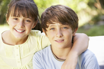 Portrait Of Brother And Sister Sitting In Garden Together