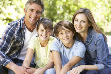 Portrait Of Happy Family Sitting In Garden Together