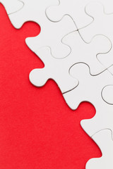 Fototapeta premium Blank white jigsaw puzzles on a bright red paper background