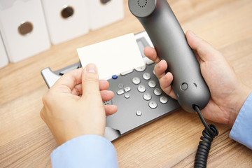businessman is reading telephone number from business card to ma