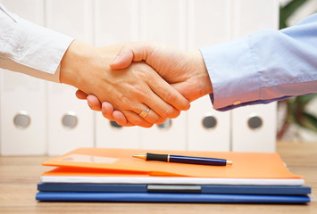 business man and woman are handshaking over documents in with of