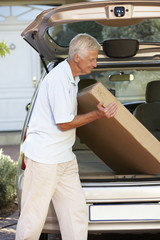 Senior Man Loading Large Package Into Back Of Car