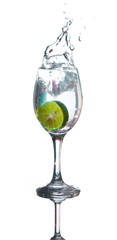 Lime splashing into glass of water on white background