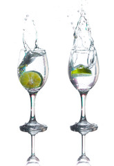 Lime splashing into glass of water on white background
