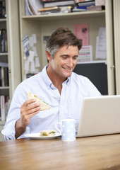 Fototapeta na wymiar Man Having Working Lunch In Home Office