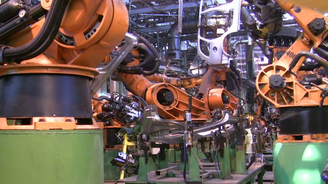 Robots weld car parts in production line at factory
