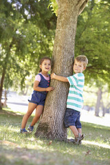 Fototapeta premium Two Children Hugging Tree In Park