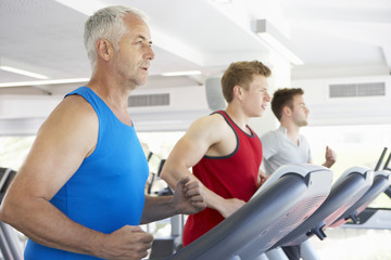Fototapeta na wymiar Group Of Men Using Running Machines In Gym